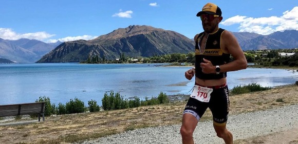 Rob Dallimore running in a triathlon beside a lake and mountains